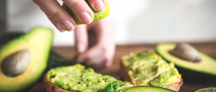 Tahta bir kesme tahtası üzerinde limon suyu sıkılarak tost üzerinde hazırlanan meyve avokado. 