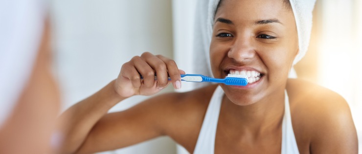 Çok fazla meyve tükettikten sonra aynanın karşısında dişlerini fırçalayan bir kadın.